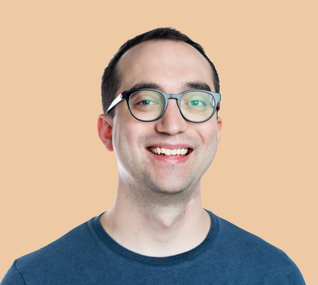 Headshot of Alex aka Friendo. He is a clean shaven white man with short dark hair, a receding hairline, and thick rimmed glasses. He is smiling.